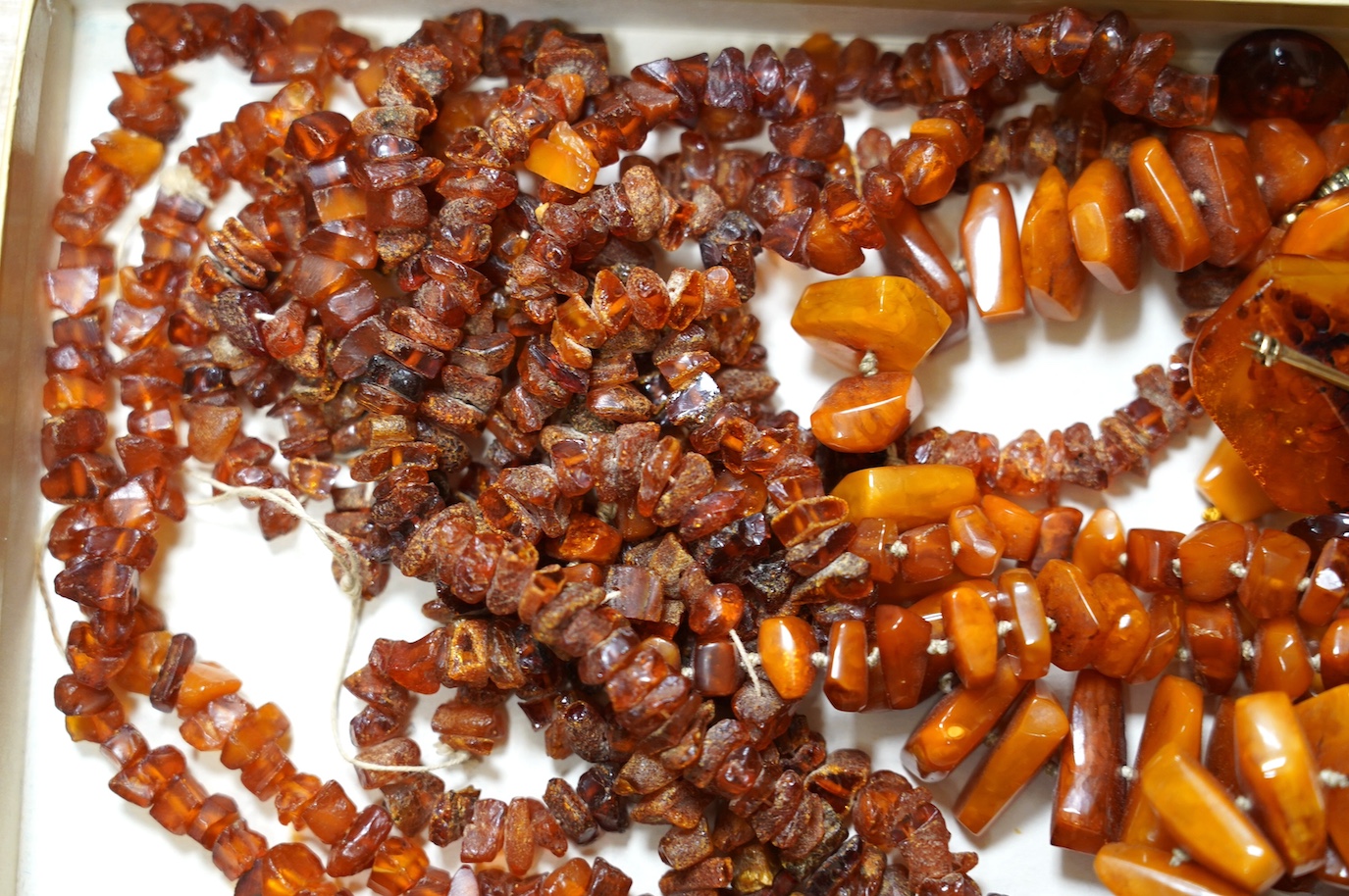 Five assorted single strand amber necklaces, including jagged pebble and unpolished, longest 176cm, together with two mounted amber rings, a pair of ear clips and a brooch, gross weight 357 grams. Condition - poor to fai